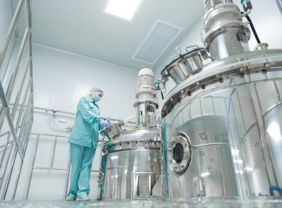 Pharmaceutical,factory,woman,worker,in,protective,clothing,operating,production,line